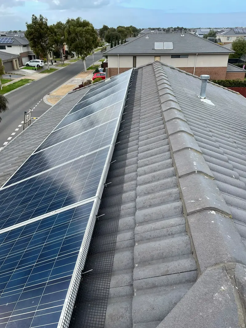 Bird proofing mesh along the edge of solar panels on a grey tile roof