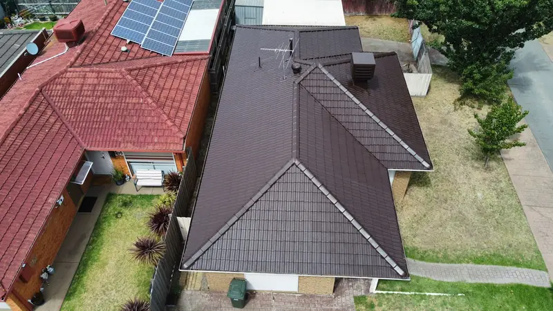 Dark brown restored tile roof next to a red tile roof, aerial view