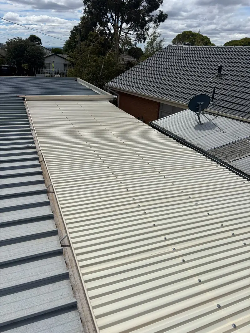 Cream corrugated metal roof sheet beside a grey tile roof