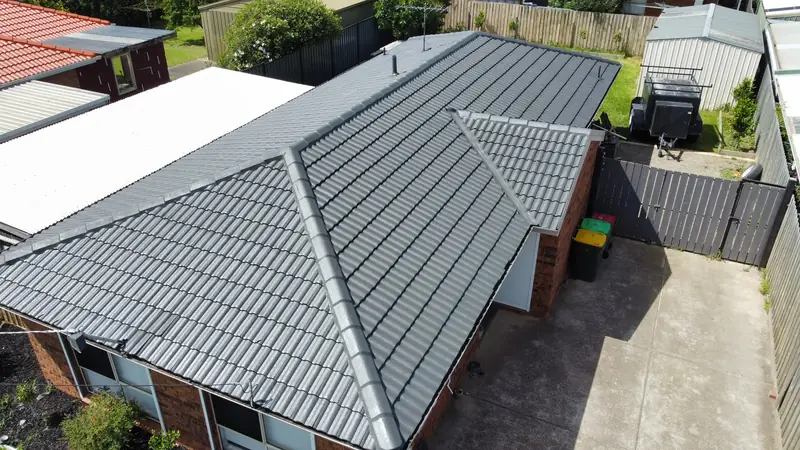 Light grey painted tile roof on a brick home, aerial view
