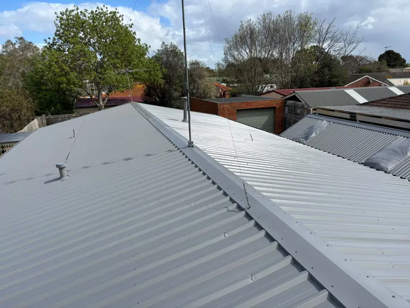 Grey corrugated metal roof with ridge capping and a flue