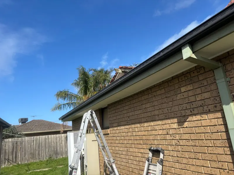 New black gutter and fascia on a brick house with ladders set up