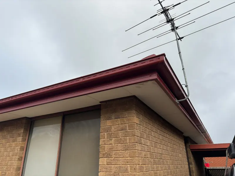 New red gutter and fascia at the corner of a brick home