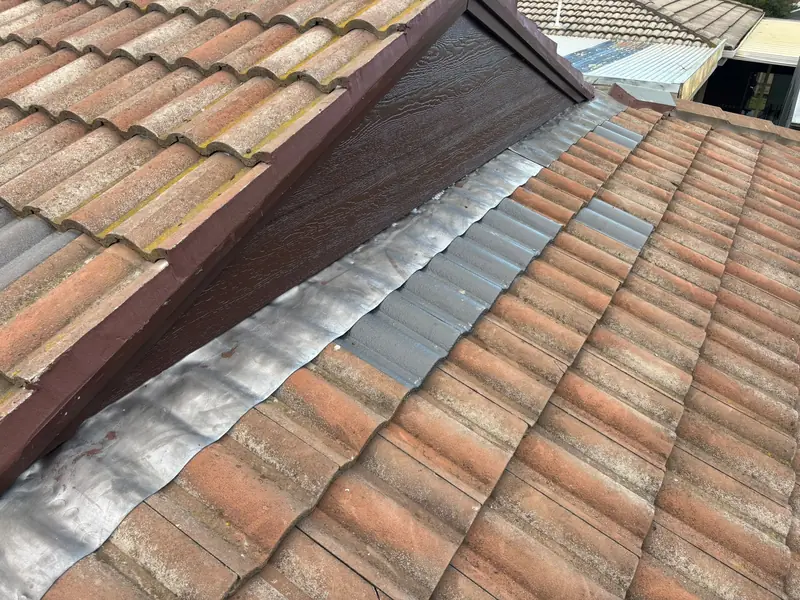 Lead flashing moulded over terracotta tiles beside a raked gable wall