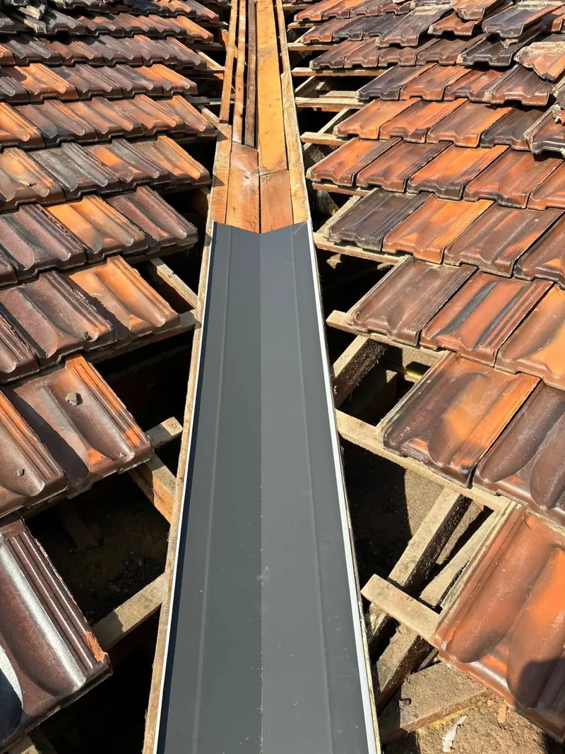 New valley iron installed along a tile roof valley with the tiles lifted either side