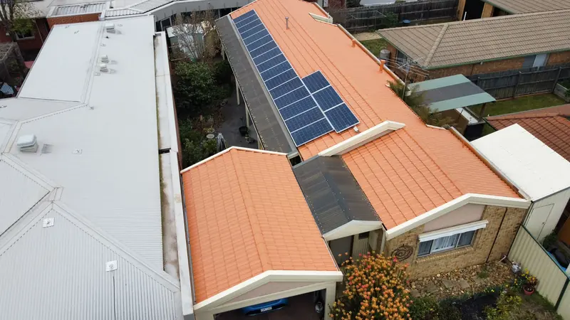 Orange tile roof with solar panels and a white sheet patio roof, aerial view
