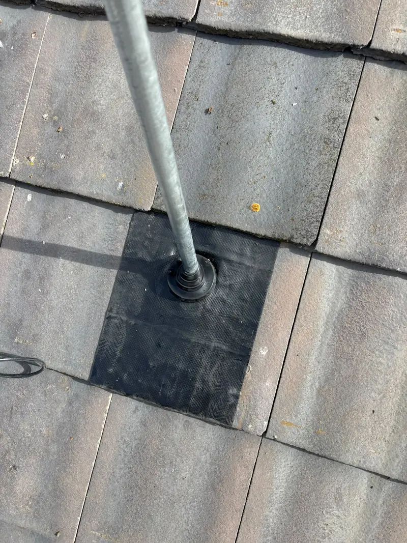 Rubber flashing boot sealing a roof pipe through concrete tiles