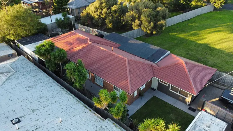 Red tile roof on a brick home with palms in the front garden, aerial view