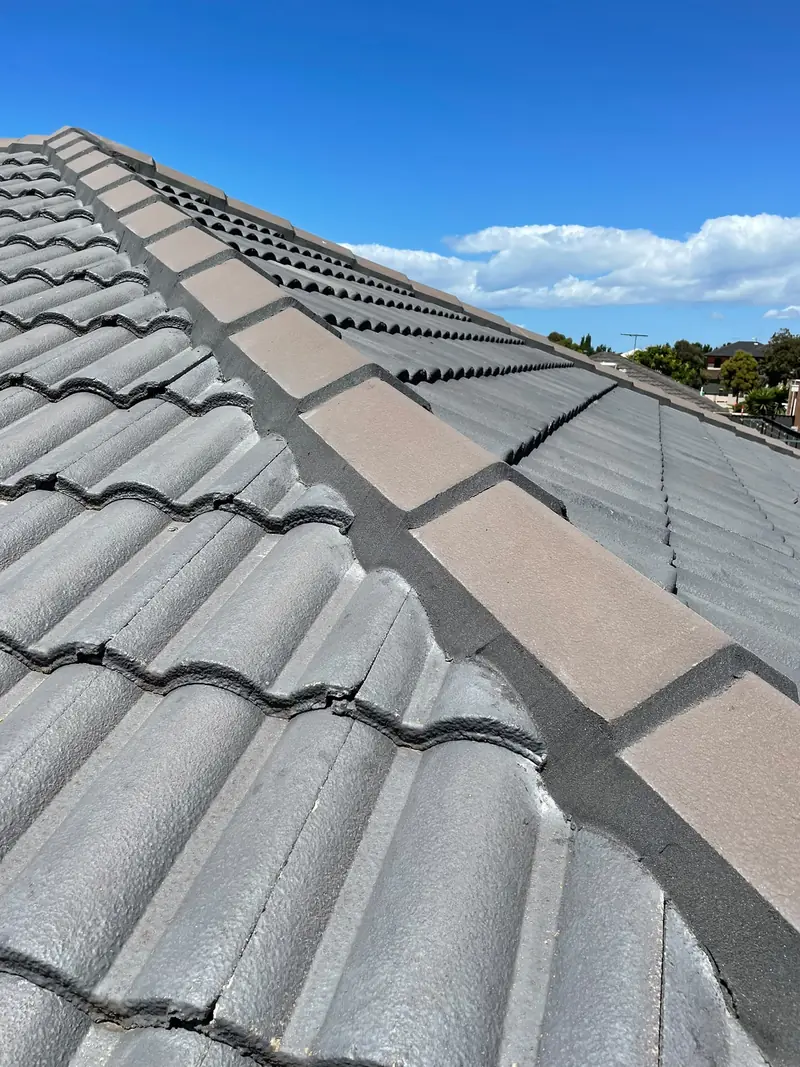 Re-pointed ridge capping on a grey tile roof with fresh dark pointing