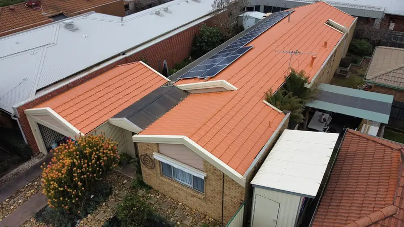 Terracotta tile roof with solar panels on a brick home, aerial view