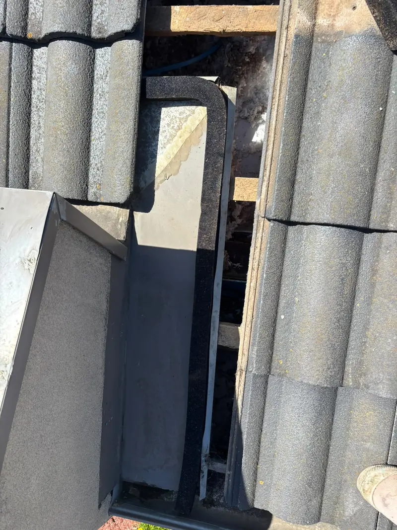 Valley and flashing work at a tile roof edge with a foam sealing strip and metal flashing